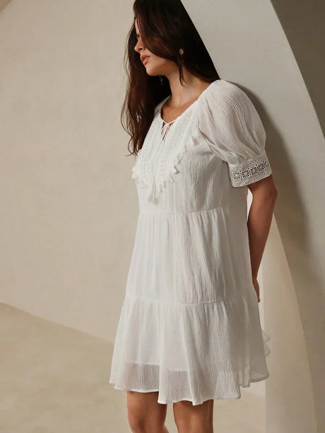 This charming white dress features a relaxed fit with delicate ruffles and intricate lace detailing, creating a breezy and.