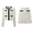 Textured white knitted jacket with black trim and decorative buttons paired with a ruffled hem skirt