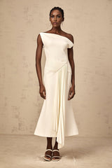 White asymmetric draped midi dress with flowing fabric and uneven hemline worn by model standing against plain background