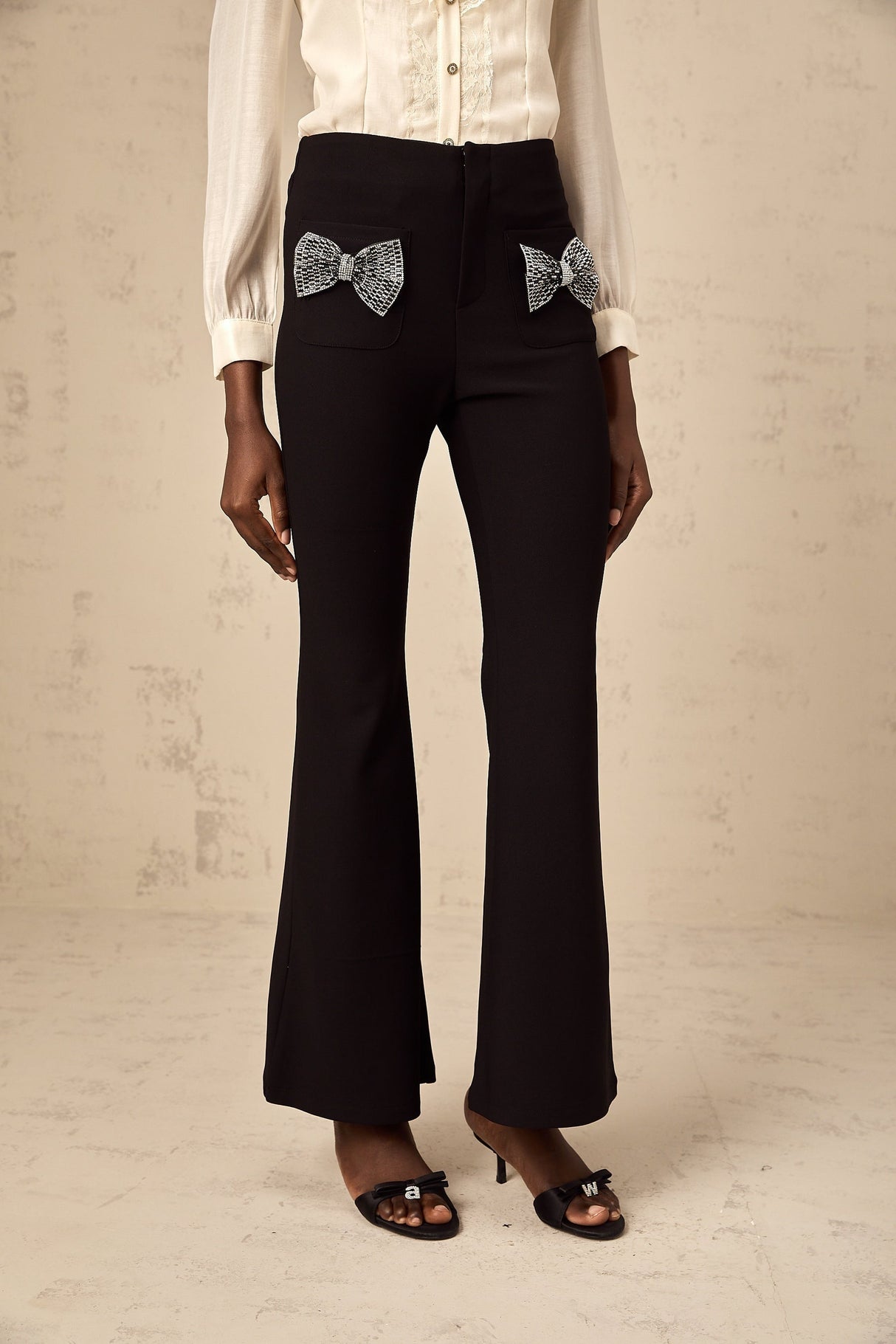 White flared trousers with decorative bow detail at waist