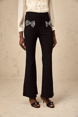 White flared trousers with decorative bow detail at waist