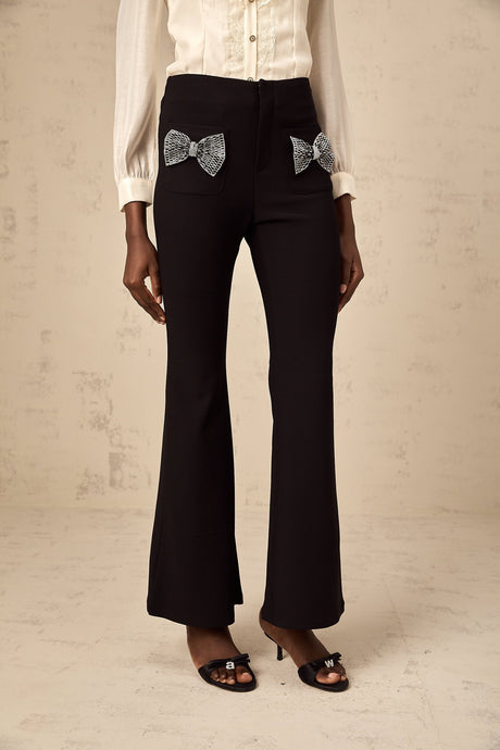 White flared trousers with decorative bow detail at waist