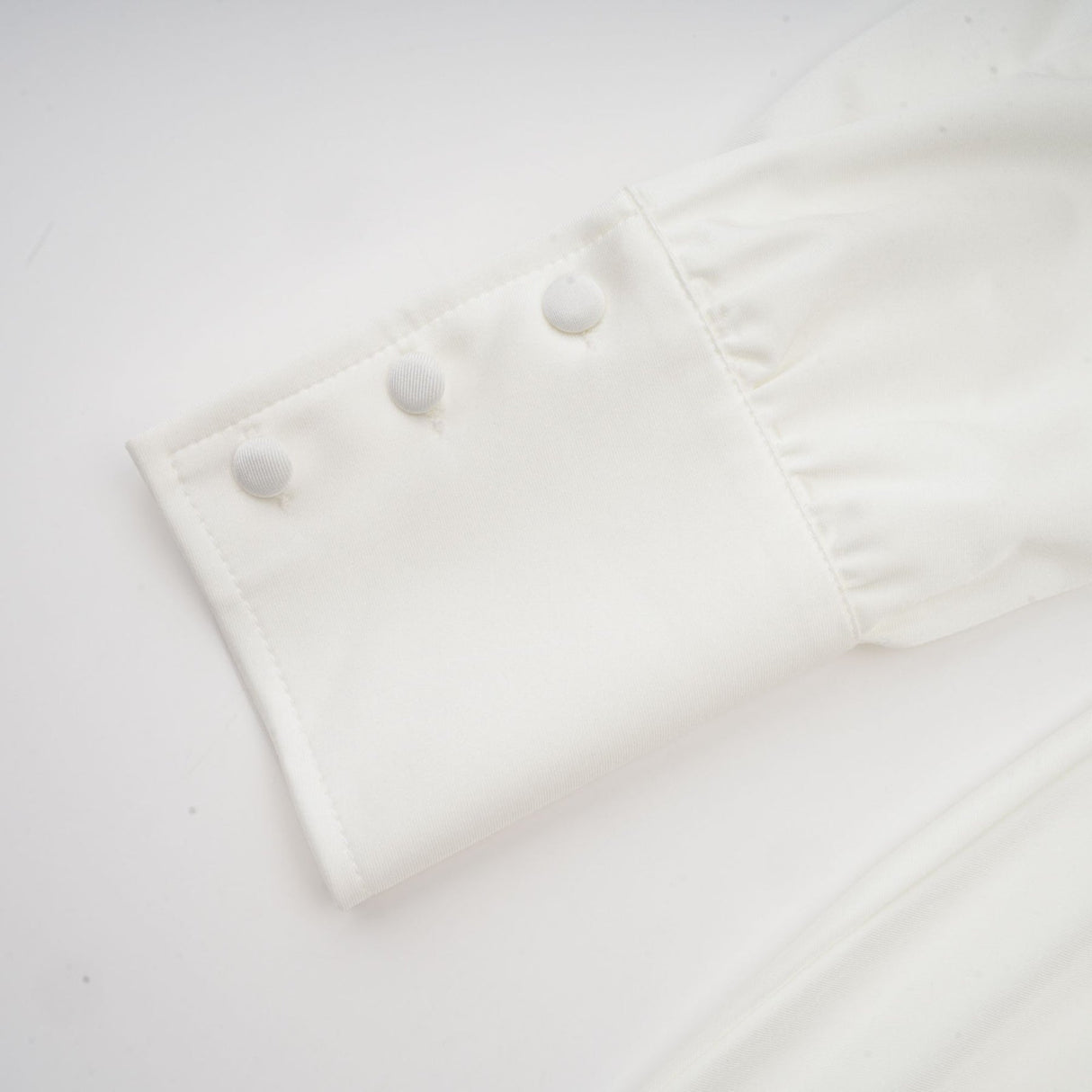 White mini dress with ruched detailing and faux flower embellishments called Maeva