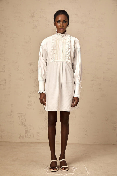 White mini shirt dress with lace trim and ruffles featuring a short length and button front closure