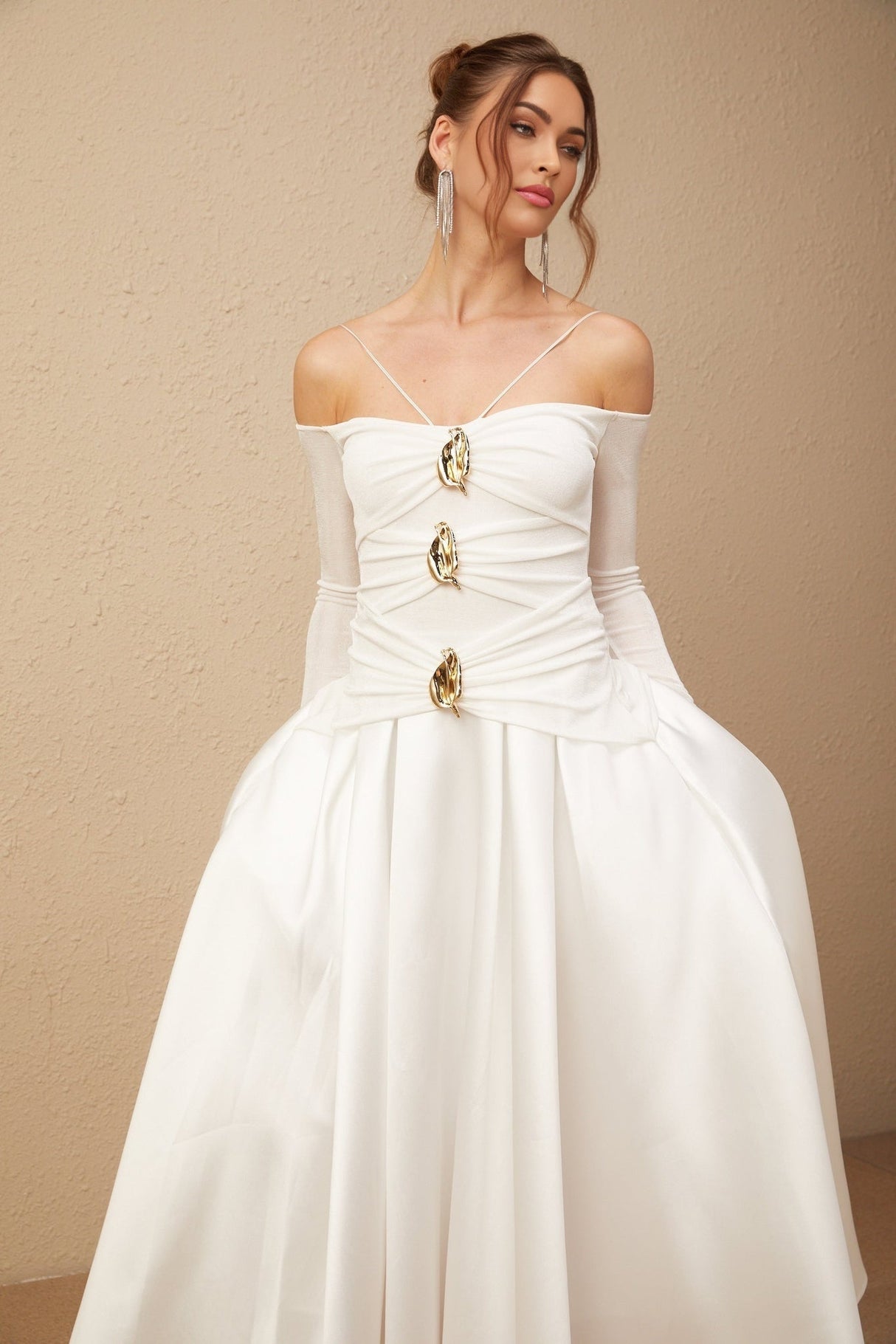 White offshoulder maxi dress with panelled design worn by model standing against plain background