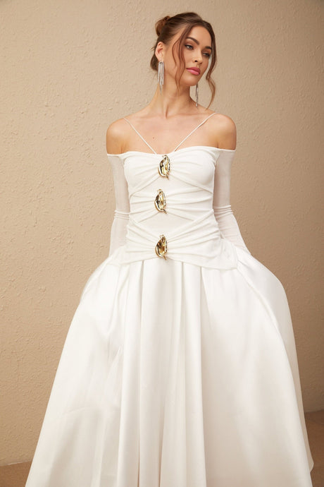 White offshoulder maxi dress with panelled design worn by model standing against plain background