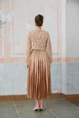 Woman wearing a beige crochet lace cardigan over a matching midi dress with delicate floral patterns standing in a neutral background