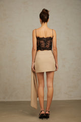 Woman wearing a beige mini skirt with ruched details and a bow accent at the waist