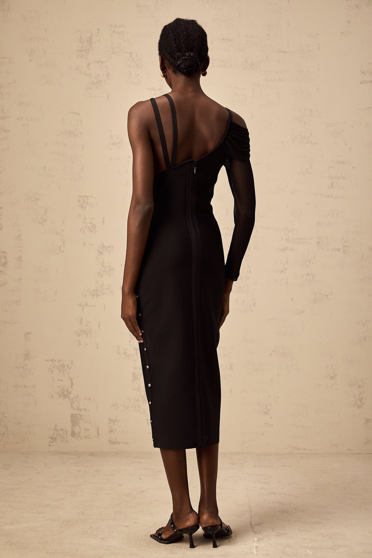 Woman wearing a black asymmetric midi dress with cutout details