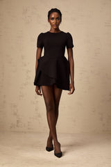 Woman wearing a black asymmetric mini dress with ruffled details