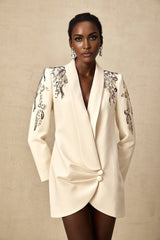 Woman wearing a black blazer dress with sequin embellishments and long sleeves
