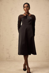 Woman wearing a black halterneck midi dress with panelled design standing in a neutral pose