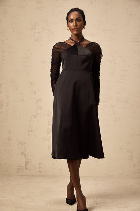 Woman wearing a black halterneck midi dress with panelled design standing in a neutral pose