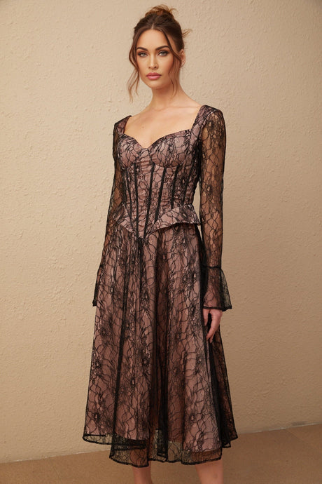 Woman wearing a black lace midi dress with flared skirt and fitted bodice standing against plain background