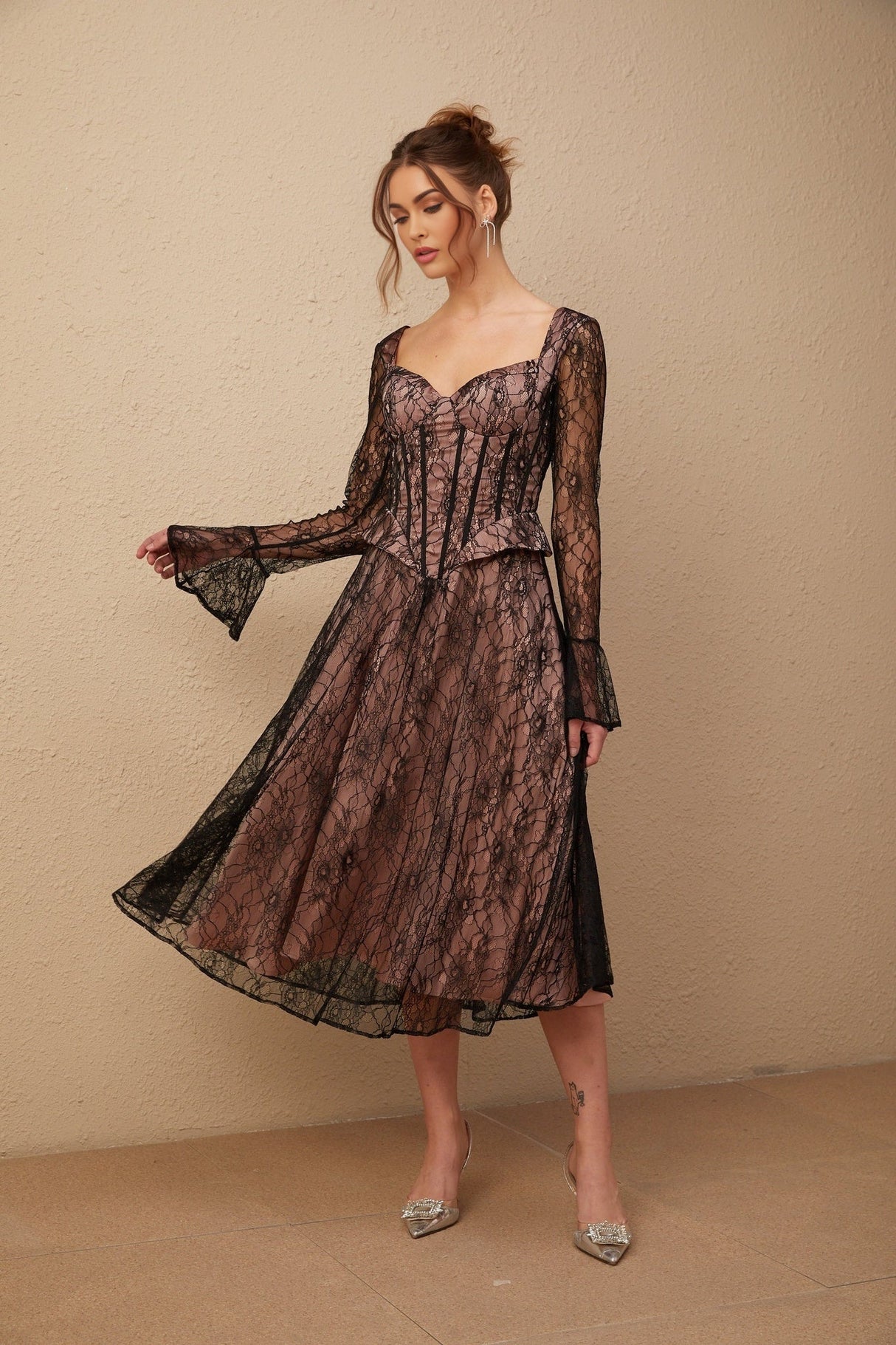 Woman wearing a black lace midi dress with flared skirt and form fitting bodice