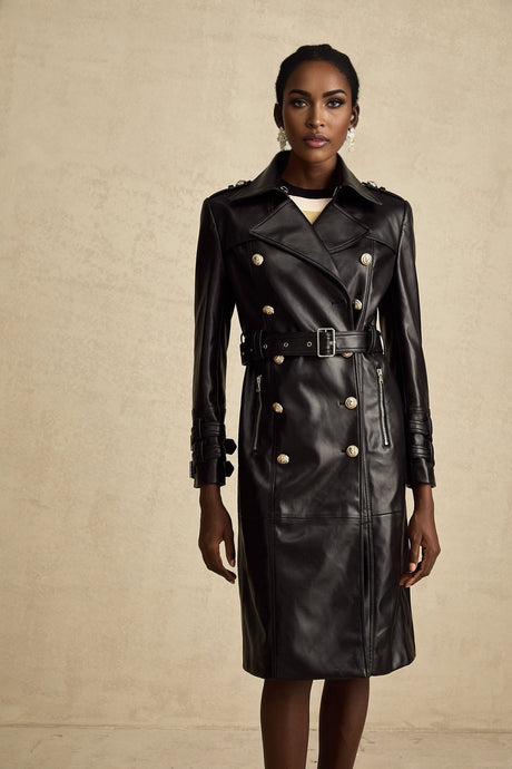 Woman wearing a black leather coat with double breasted front and belt cinched at waist