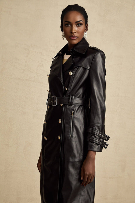 Woman wearing a black leather coat with doublebreasted front and belted waist
