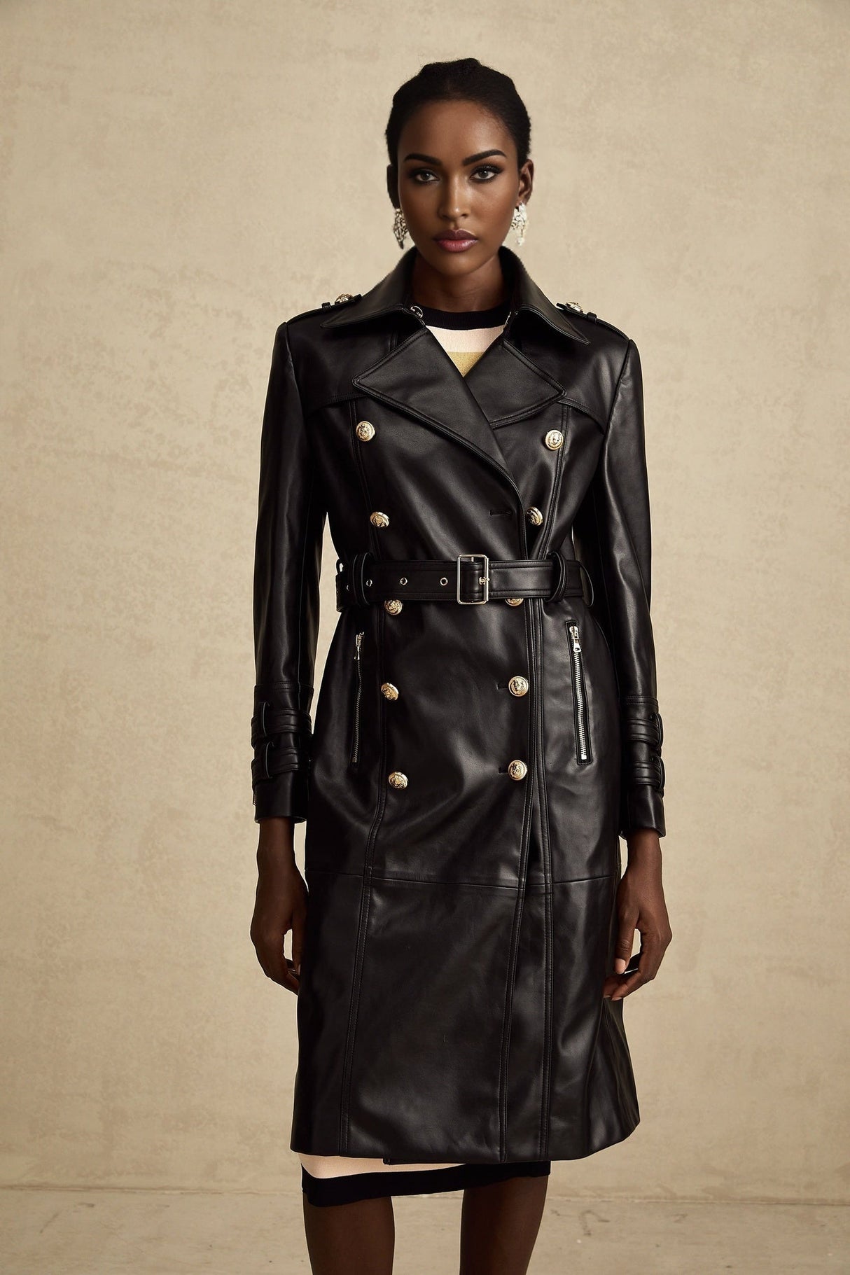 Woman wearing a black leather coat with doublebreasted front closure and belt at waist