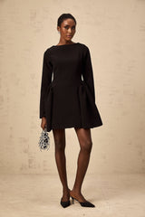Woman wearing a black long sleeve mini dress with a flared skirt