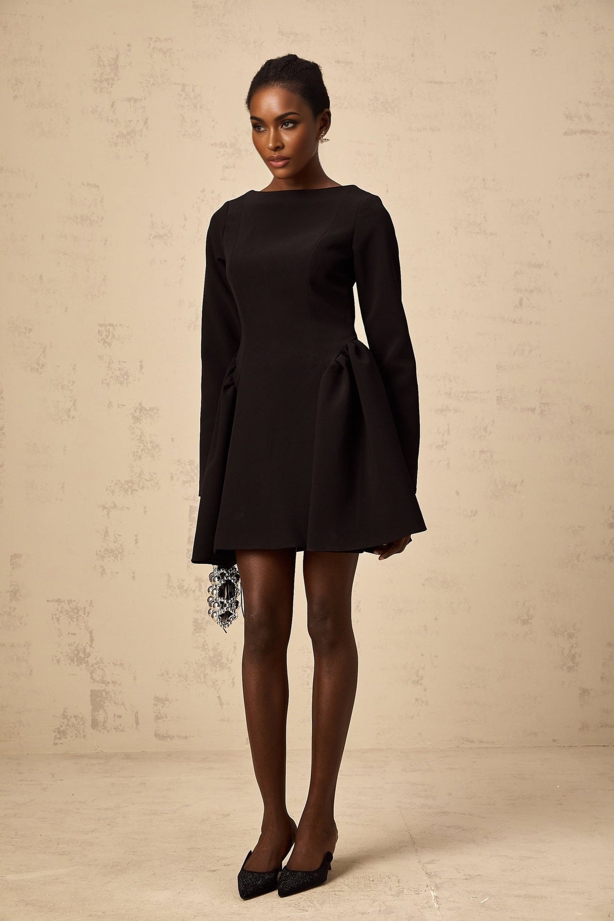 Woman wearing a black longsleeve mini dress with a flared skirt