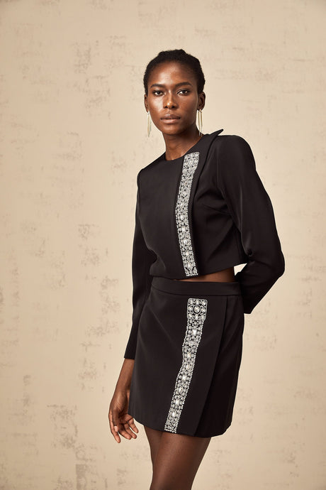 Woman wearing a black matching set consisting of a crystalembellished top and skirt named Nadia