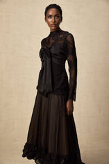 Woman wearing a black midi dress with floral lace panels and sheer details