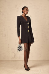 Woman wearing a black mini dress with a blazer style top featuring decorative lion head details on the shoulders