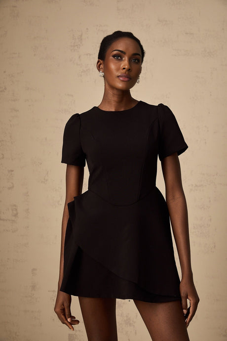 Woman wearing a black mini dress with asymmetric design and ruffled details