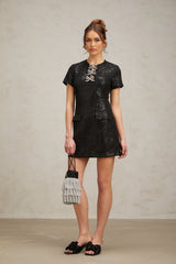 Woman wearing a black mini dress with glitter accents