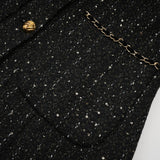 Woman wearing a black mini dress with sequin panels and tweed fabric short sleeves and form fitting silhouette