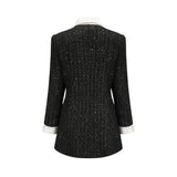Woman wearing a black mini dress with tweed fabric and sequin panels Audrey style dress with short length and mixed textures