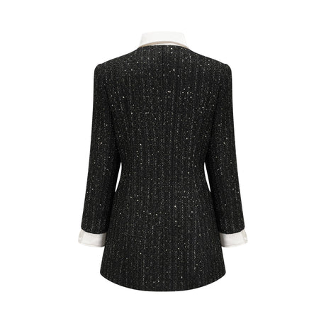 Woman wearing a black mini dress with tweed fabric and sequin panels Audrey style dress with short length and mixed textures
