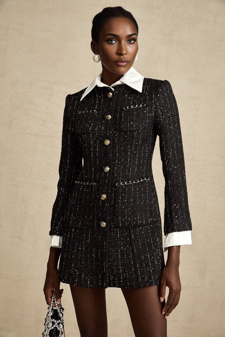 Woman wearing a black mini dress with tweed fabric and sequin panels short sleeves and a high neckline
