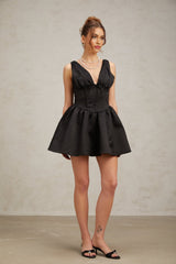 Woman wearing a black mini dress with Vneck and flared skirt