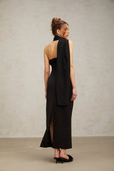 Woman wearing a black oneshoulder midi dress with draped fabric detail