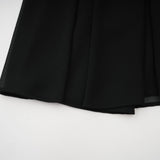 Woman wearing a black pleated midi dress with button front detail and short sleeves