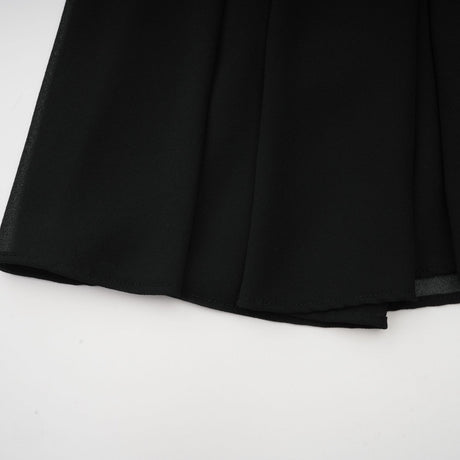 Woman wearing a black pleated midi dress with button front detail and short sleeves