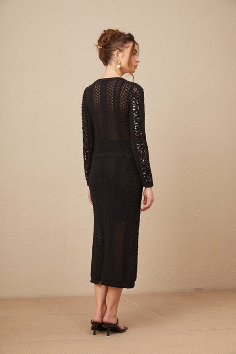 Woman wearing a black sequined matching set consisting of a crochet knit cardigan and skirt named Ophelie