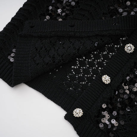 Woman wearing a black sequined matching set with crochet knit cardigan and skirt