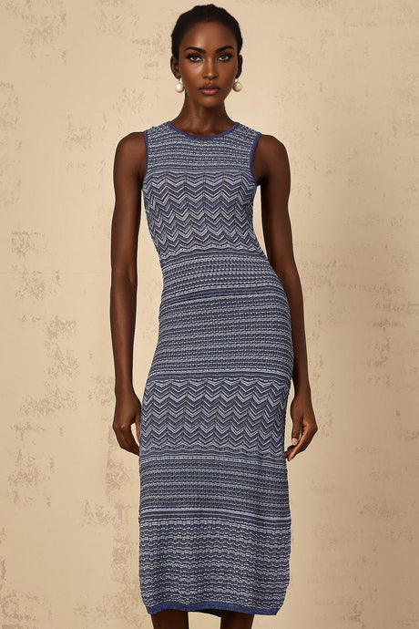 Woman wearing a blue crochet knit midi dress with wavy pattern standing against a plain background