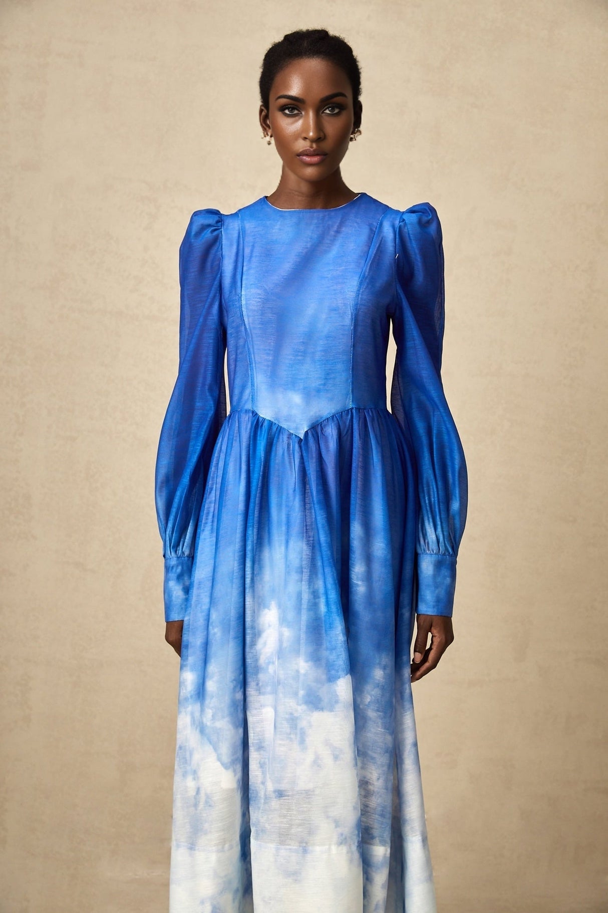 Woman wearing a blue gradient pleated midi dress with a flowing silhouette and ombre effect from light to dark blue