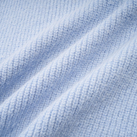 Woman wearing a blue knit blouse and matching skirt set standing in a neutral background