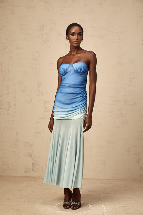 Woman wearing a blue ombre midi dress with mesh overlay standing against a plain background