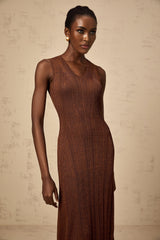 Woman wearing a brown knitted midi dress with cutout details on a plain background