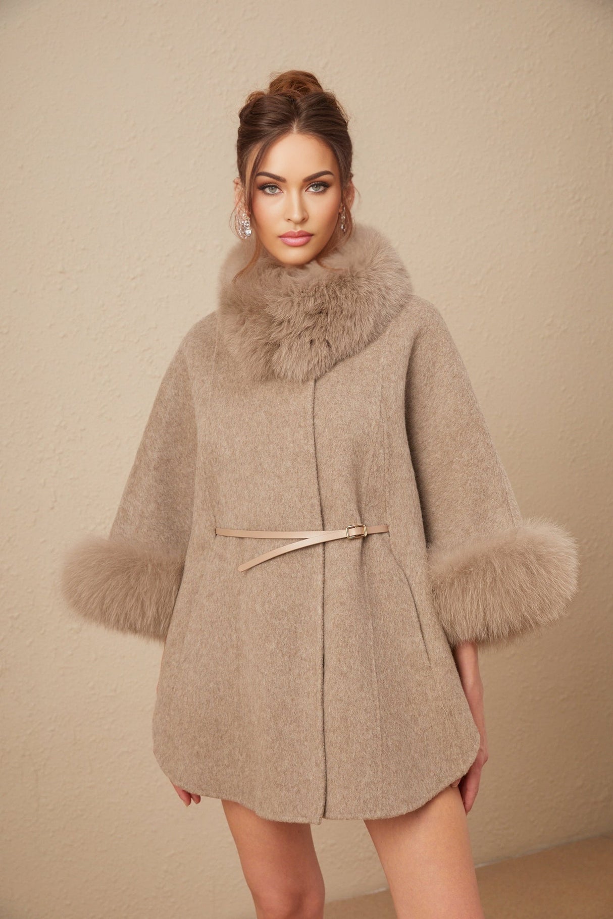 Woman wearing a brown wool cape coat with fur trim and belt cinched at the waist