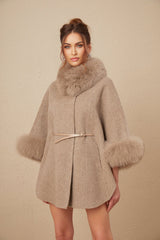 Woman wearing a brown wool cape coat with fur trim and belt cinched at the waist