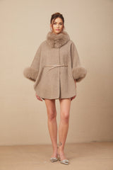 Woman wearing a brown wool cape coat with fur trim and belt cinched at the waist
