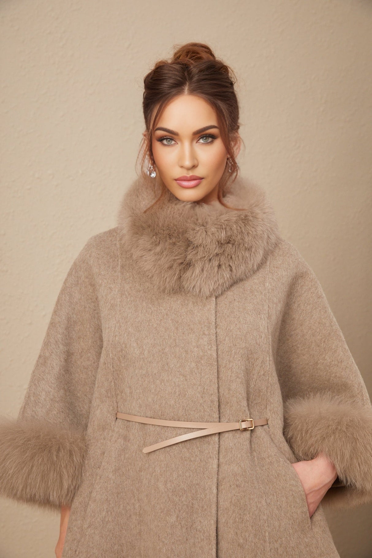 Woman wearing a brown wool cape coat with fur trim and belt cinched at the waist