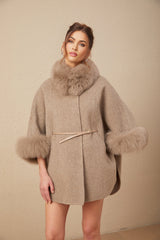 Woman wearing a brown wool cape coat with fur trim and belt cinched at the waist
