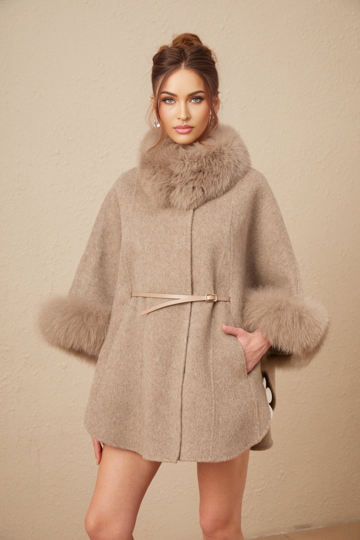 Woman wearing a brown wool cape coat with fur trim and belt cinched at waist